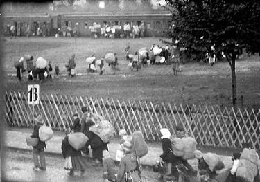 Polacy pod eskortą funkcjonariuszy policji w drodze do pociągu (data i miejscowość nieustalona). (fot. J&oacute;zef Macikowski; w zbiorach elektronicznych OKŚZpNP w Katowicach).